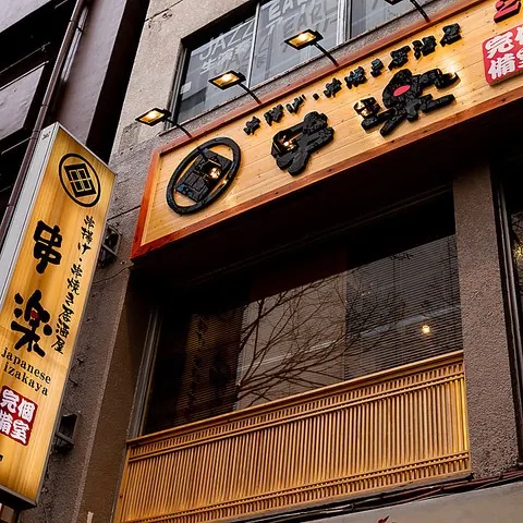 木のテーブル席とカウンター席が並ぶ焼き鳥居酒屋の店内